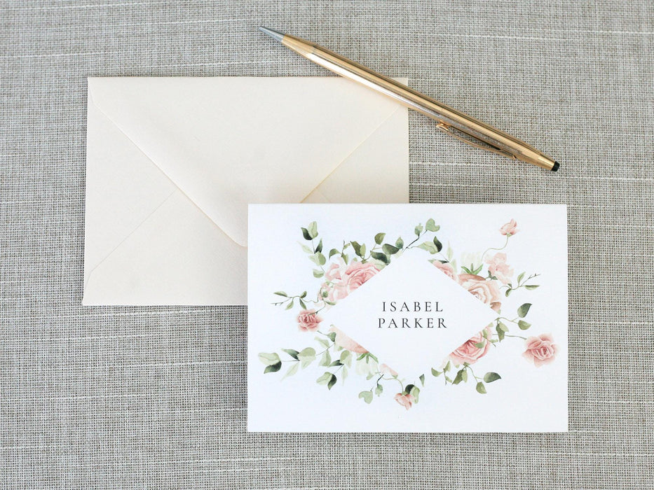 a card with a floral wreath on it next to a pen and envelope