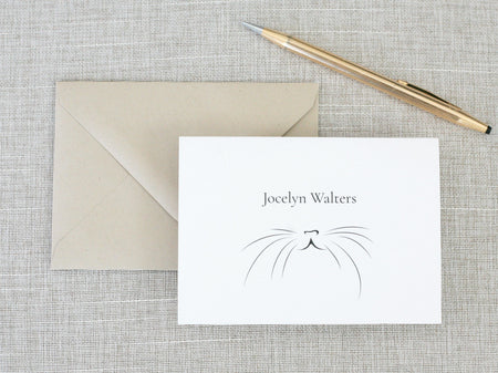 a card with a cat's face on it next to a pen