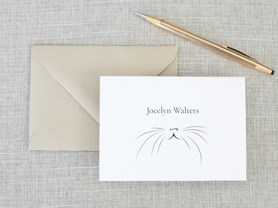 a card with a cat's face on it next to a pen