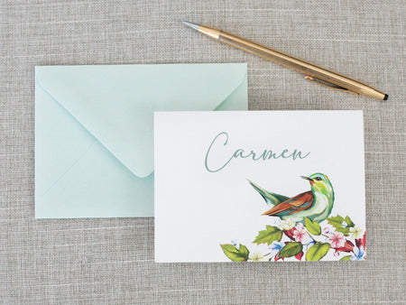 a card with a bird on it next to a pen and envelope