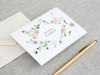 a card with a floral design and a pen on a table