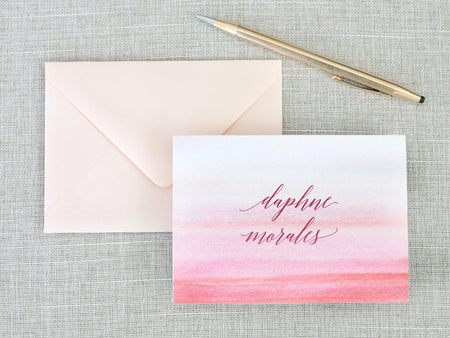 a pink and red watercolored greeting card with a pen