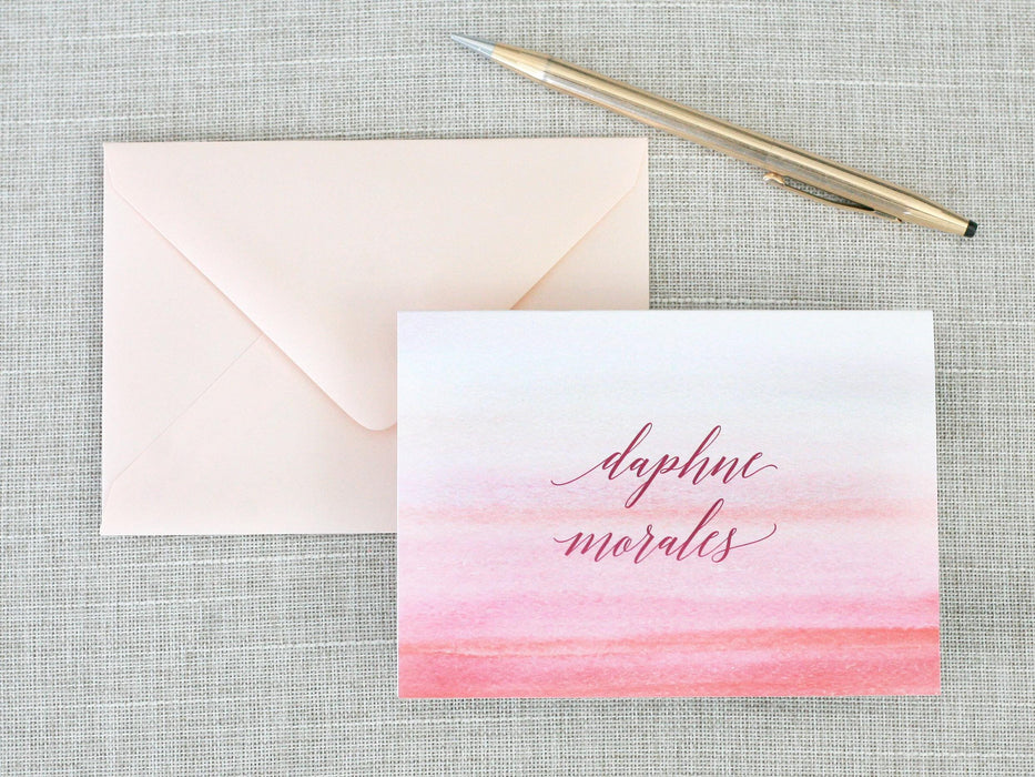 a pink and red watercolored greeting card with a pen