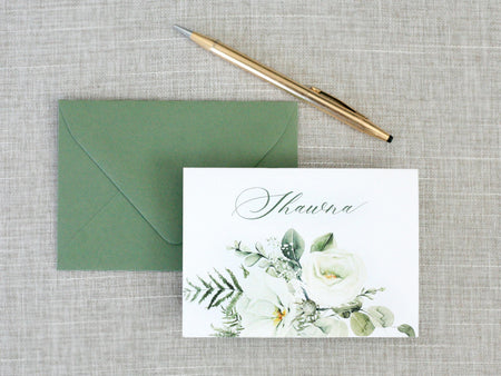 a card with a flower on it next to a pen and envelope